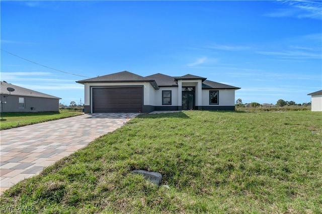 prairie-style home featuring a front lawn, a garage, decorative driveway, and stucco siding