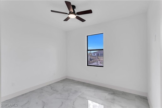 spare room featuring marble finish floor, baseboards, and a ceiling fan