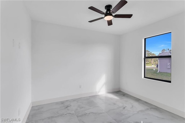 empty room with marble finish floor, baseboards, and a ceiling fan