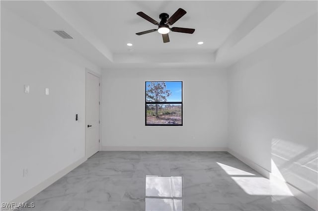 unfurnished room featuring visible vents, baseboards, a raised ceiling, a ceiling fan, and marble finish floor