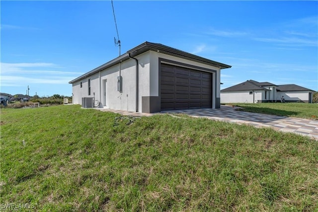 view of side of property with central air condition unit, a yard, an attached garage, concrete driveway, and stucco siding