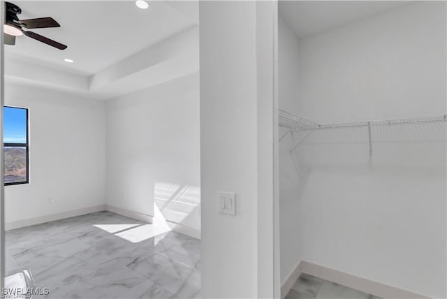 walk in closet with marble finish floor and a ceiling fan