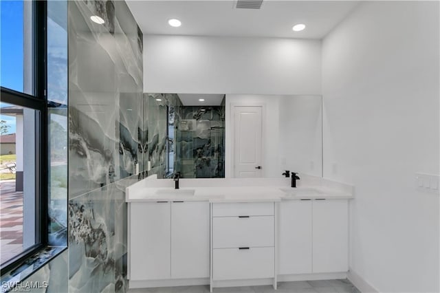 bathroom featuring a marble finish shower, visible vents, double vanity, and a sink