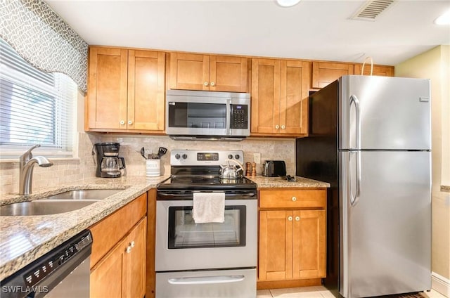 100 Forest Lakes Blvd Unit 110, Naples, FL 34105 - kitchen featuring stainless steel appliances, a sink, light stone countertops, tasteful backsplash, and brown cabinets