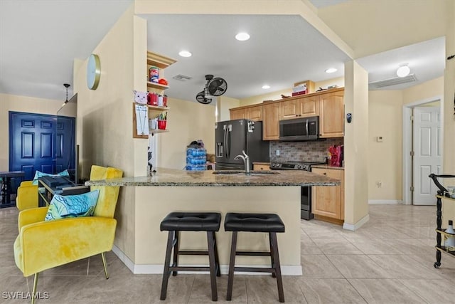 605 SE 22nd St, Cape Coral, FL 33990 - kitchen featuring light tile patterned floors, dark stone countertops, appliances with stainless steel finishes, decorative backsplash, and a breakfast bar area