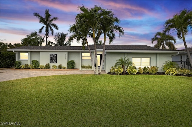 single story home featuring a front lawn, stucco siding, and driveway