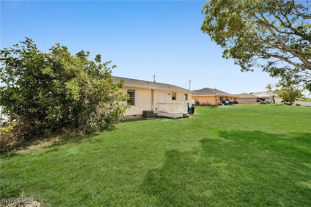 view of green lawn featuring a wooden deck and cooling unit