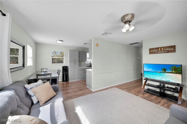 living room with wood finished floors, ceiling fan, and baseboards