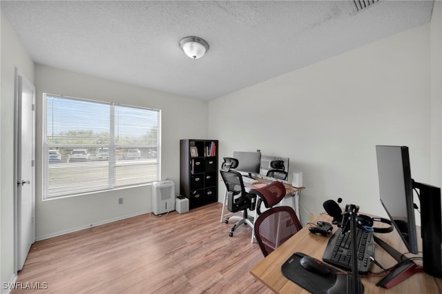 office area with light wood-style floors, a textured ceiling, and baseboards