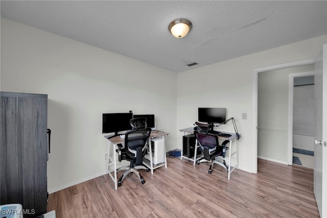 office with wood finished floors, baseboards, and a textured ceiling