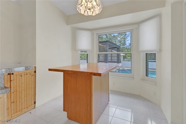 interior space with a kitchen island, a chandelier, light tile patterned floors, and light countertops