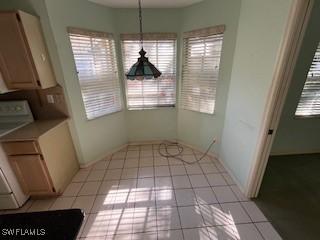 unfurnished dining area featuring plenty of natural light, light tile patterned floors, and baseboards