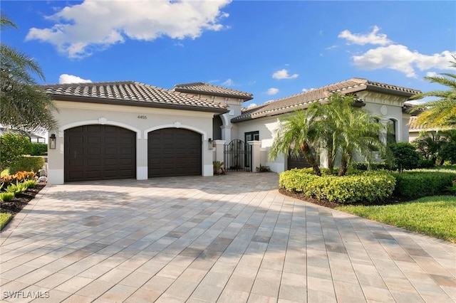4455 Caldera Cir, Naples, FL 34119 - mediterranean / spanish-style house featuring stucco siding, an attached garage, decorative driveway, and a tiled roof