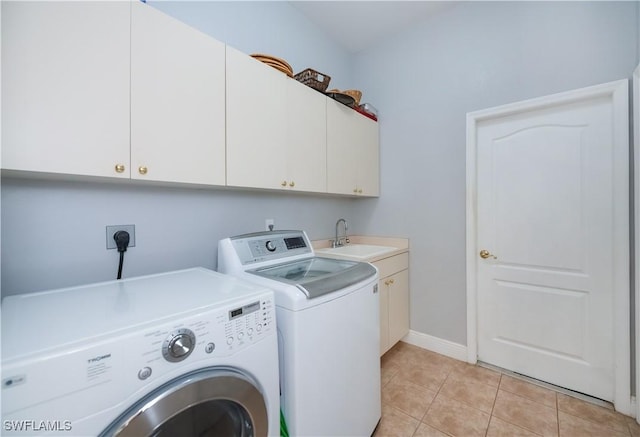 clothes washing area featuring a sink, washing machine and dryer, baseboards, cabinet space, and light tile patterned floors