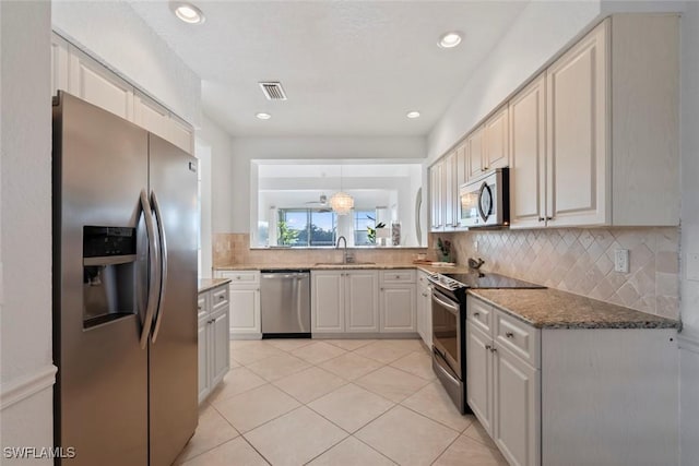 3570 Haldeman Creek Dr Unit 134, Naples, FL 34112 - kitchen with visible vents, a sink, stainless steel appliances, decorative backsplash, and stone countertops