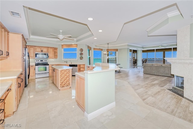 15220 Portside Dr Unit 301, Fort Myers, FL 33908 - kitchen with light brown cabinetry, stainless steel appliances, a raised ceiling, a ceiling fan, and a center island
