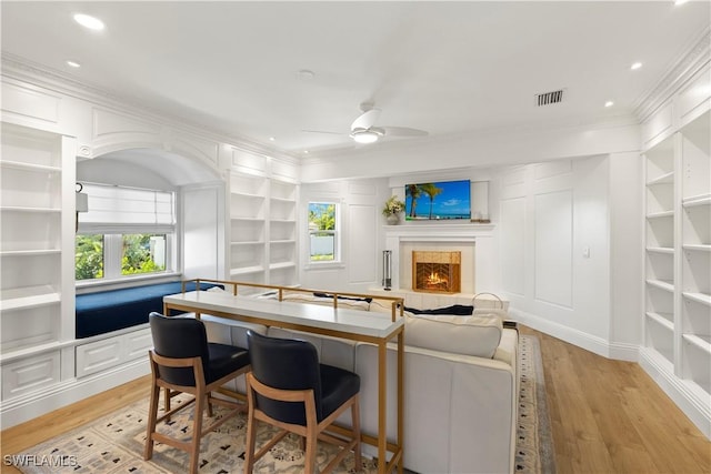 8451 Casa Del Rio Ln, Fort Myers, FL 33919 - interior space with ornamental molding, a warm lit fireplace, visible vents, light wood finished floors, and built in shelves