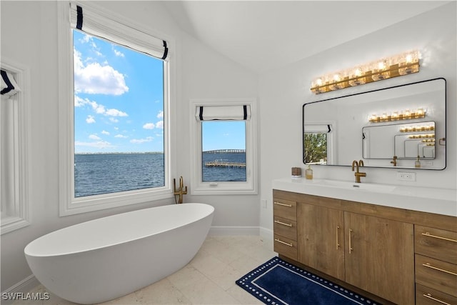 8451 Casa Del Rio Ln, Fort Myers, FL 33919 - full bathroom with baseboards, a freestanding tub, a water view, vanity, and vaulted ceiling
