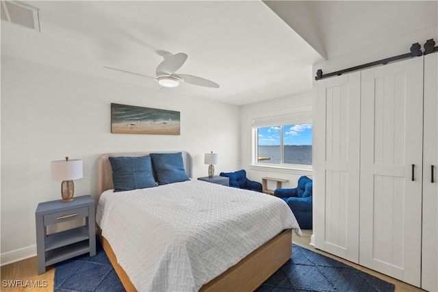 8451 Casa Del Rio Ln, Fort Myers, FL 33919 - bedroom with a ceiling fan, visible vents, a barn door, wood finished floors, and baseboards