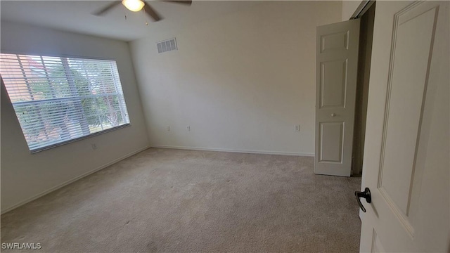 spare room with ceiling fan, light carpet, and baseboards