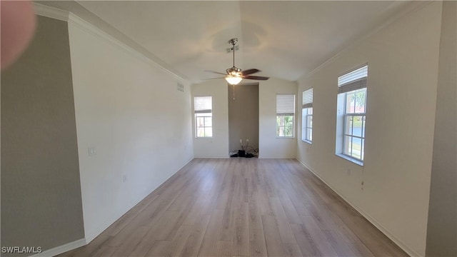 spare room featuring light wood-style flooring, a ceiling fan, and baseboards
