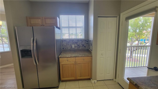 kitchen featuring stainless steel fridge, light tile patterned flooring, plenty of natural light, and decorative backsplash