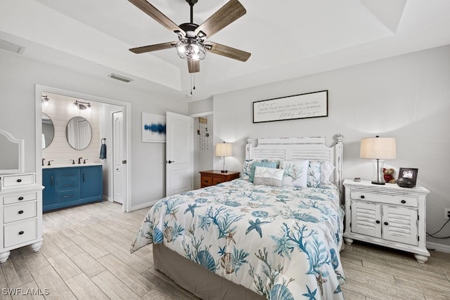 bedroom featuring light wood finished floors, visible vents, and a raised ceiling