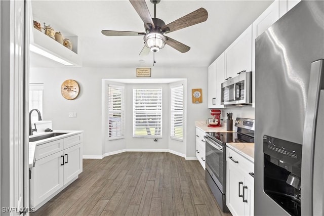 kitchen featuring light countertops, a sink, dark wood-type flooring, baseboards, and appliances with stainless steel finishes