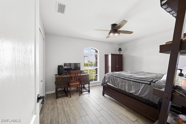 bedroom featuring visible vents, light wood finished floors, baseboards, and a ceiling fan