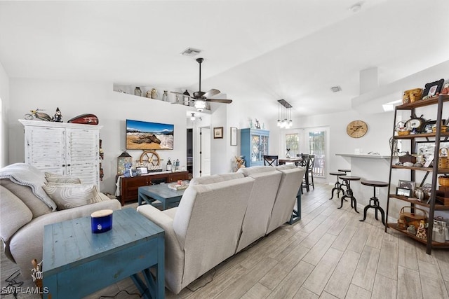 living room with vaulted ceiling, visible vents, light wood finished floors, and ceiling fan