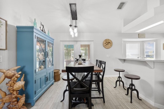 dining room with light wood finished floors, french doors, visible vents, and baseboards