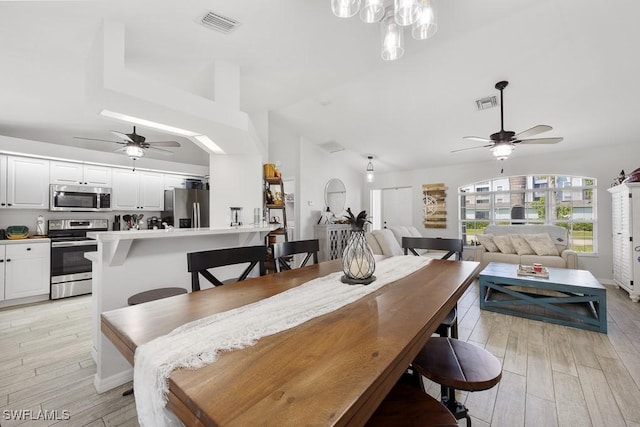 dining room featuring ceiling fan, vaulted ceiling, visible vents, and light wood-type flooring