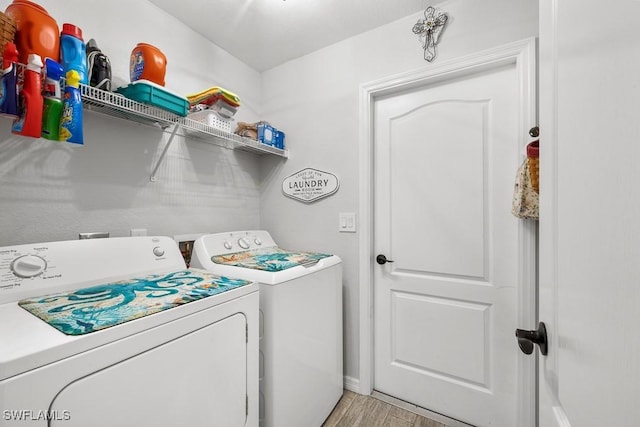 clothes washing area featuring independent washer and dryer, light wood-type flooring, baseboards, and laundry area