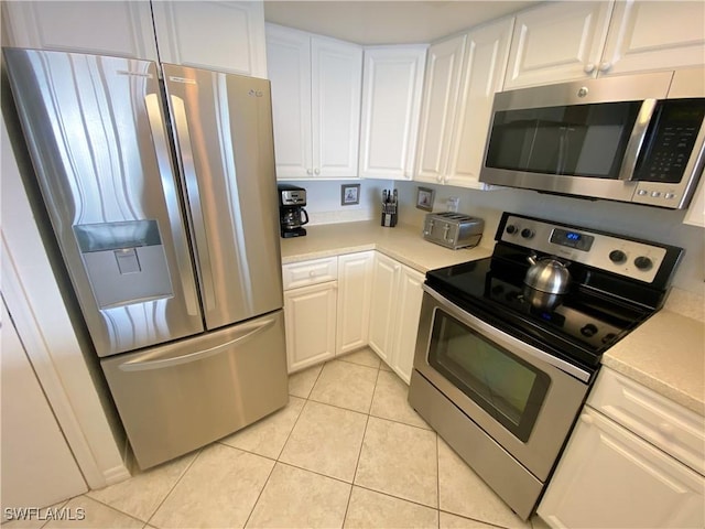 kitchen with light tile patterned floors, white cabinetry, stainless steel appliances, and light countertops