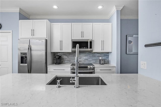 9719 Acqua Ct Unit 241, Naples, FL 34113 - kitchen with appliances with stainless steel finishes, light stone countertops, crown molding, backsplash, and white cabinets