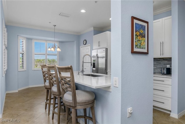 9719 Acqua Ct Unit 241, Naples, FL 34113 - kitchen with stainless steel fridge, a breakfast bar area, light tile patterned flooring, white cabinets, and crown molding