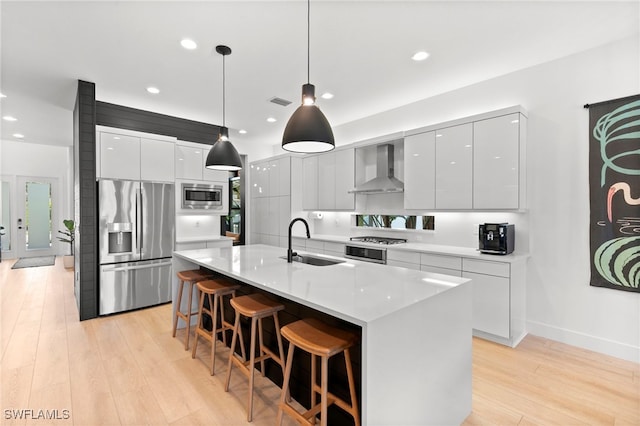 4045 Nova Ln, Naples, FL 34119 - kitchen with modern cabinets, a sink, wall chimney range hood, light wood-type flooring, and appliances with stainless steel finishes
