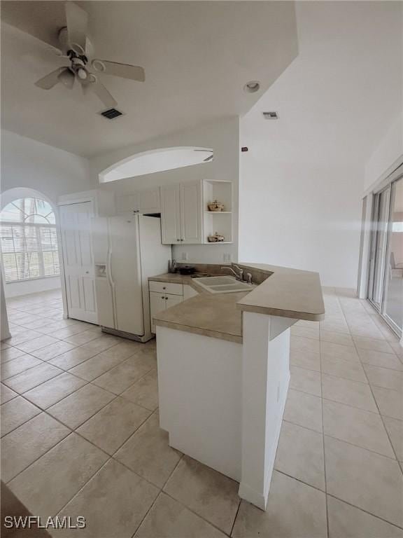 kitchen with a peninsula, light tile patterned flooring, white refrigerator with ice dispenser, and a sink