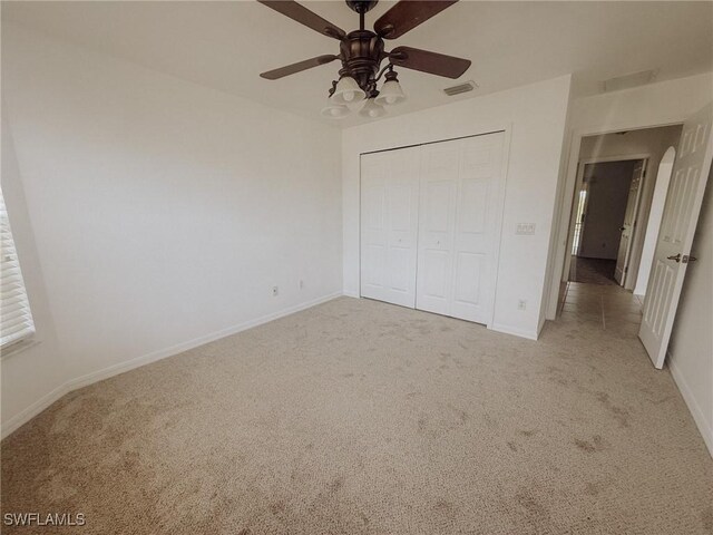 unfurnished bedroom featuring baseboards, visible vents, a closet, and light colored carpet