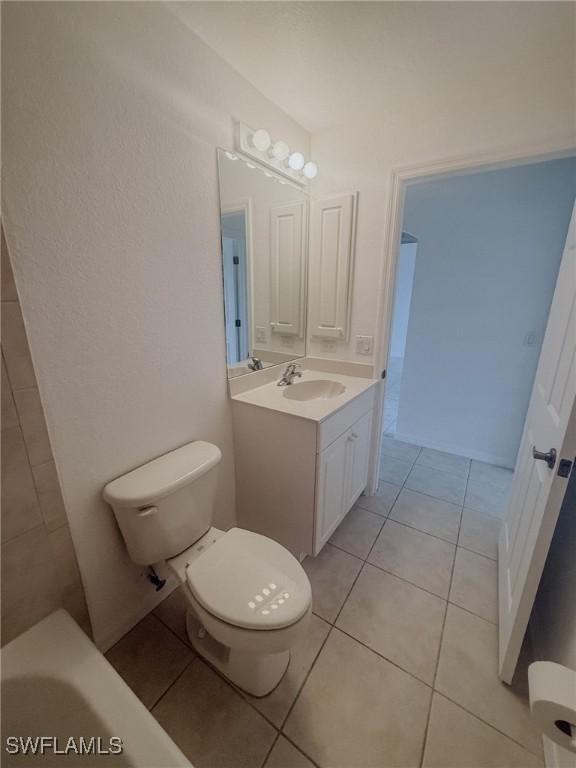 full bathroom with toilet, tile patterned flooring, a tub, and vanity