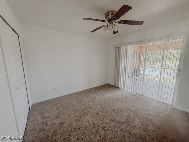 empty room with a ceiling fan, carpet floors, and baseboards