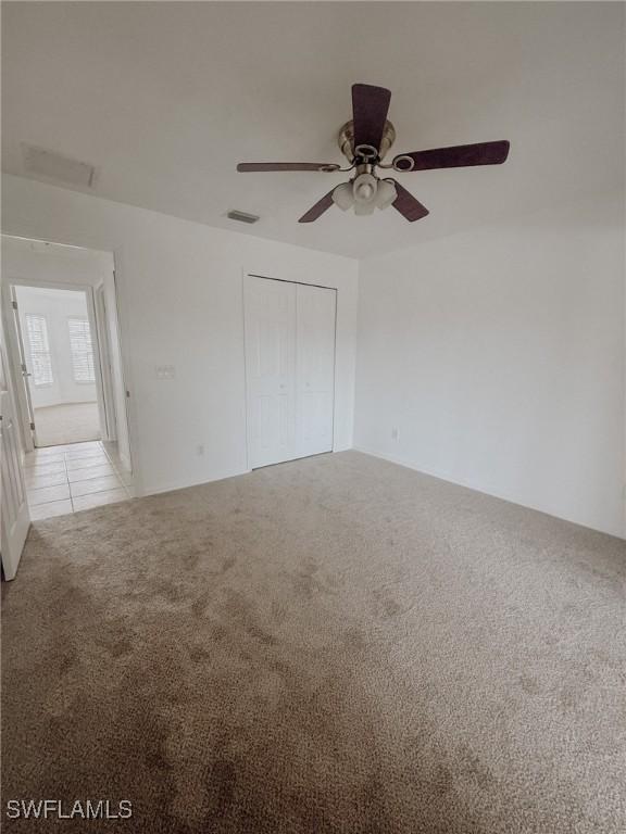 unfurnished room with ceiling fan, light colored carpet, and visible vents