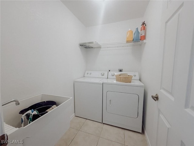 clothes washing area with baseboards, light tile patterned floors, washing machine and clothes dryer, and laundry area