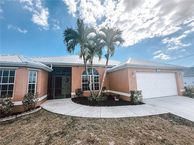 ranch-style home with driveway, metal roof, stucco siding, and a garage