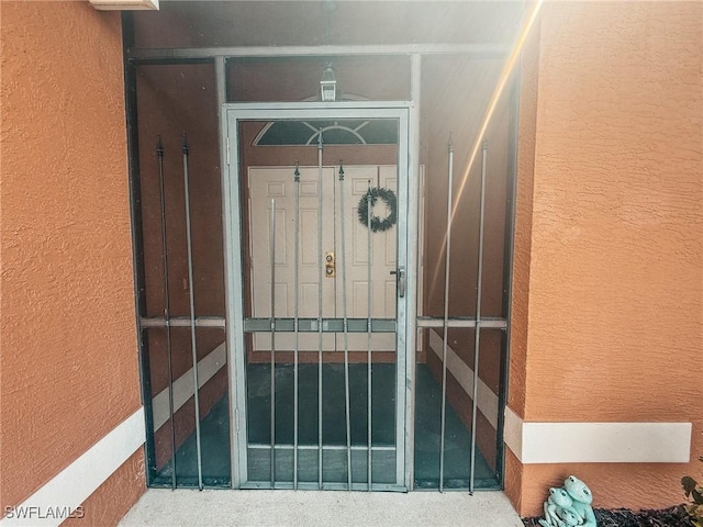 view of exterior entry featuring a gate and stucco siding