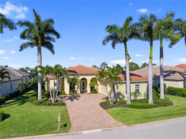 mediterranean / spanish home featuring stucco siding, a tile roof, decorative driveway, and a garage