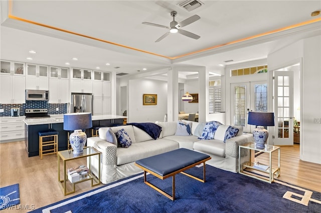 living room with wood finished floors, visible vents, ceiling fan, and french doors