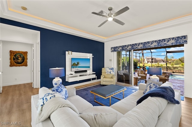 living room with baseboards, wood finished floors, ceiling fan, and crown molding