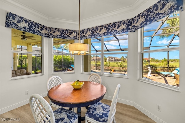 dining area with light wood-type flooring, baseboards, and crown molding