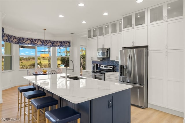 kitchen with white cabinets, light wood-style flooring, a sink, recessed lighting, and appliances with stainless steel finishes